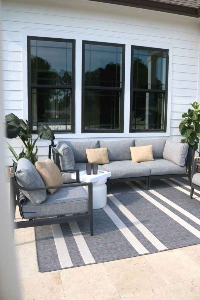 A white and black windows house and grey sofa and cushion and mat on the floor