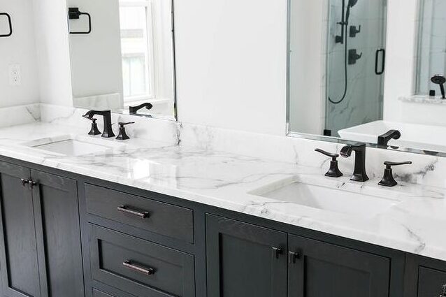 A white bathroom and black faucets and mirror on the wall