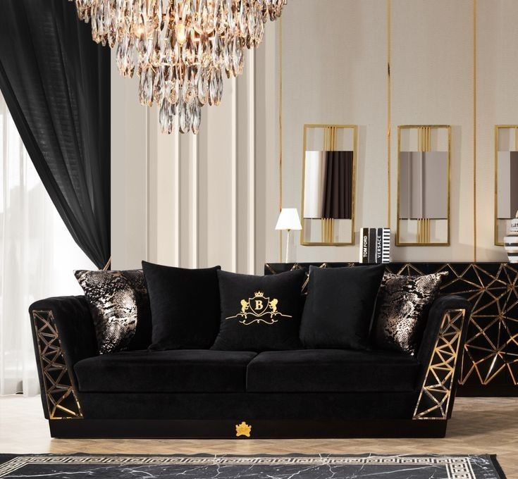 A black velvet sofa with gold accents and mirror on the wall