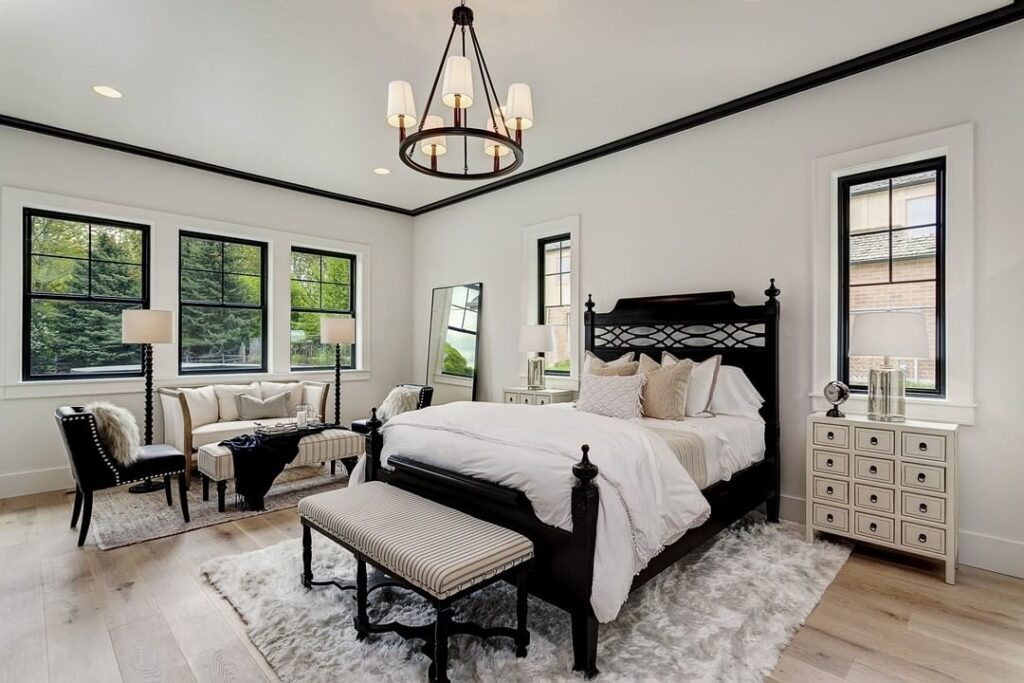 A bedroom with black framed windows and bed and rug on floor 