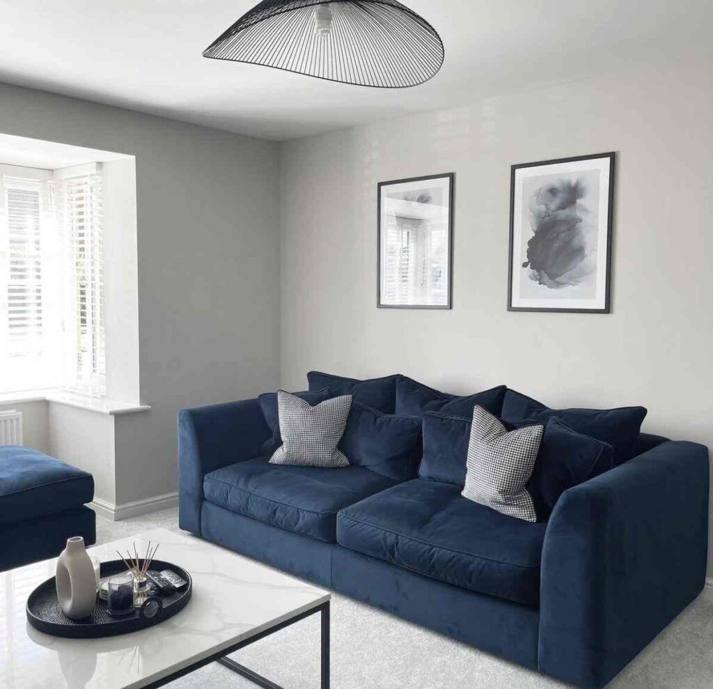 A living room with blue sofa and black framed painting on wall 