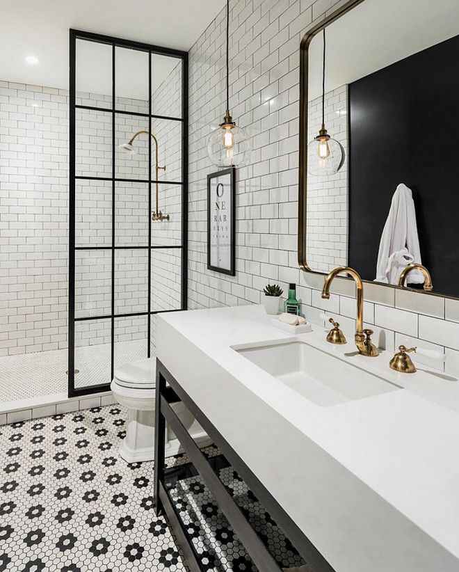 A white bathroom and white sink and copper tap and lights above the wall