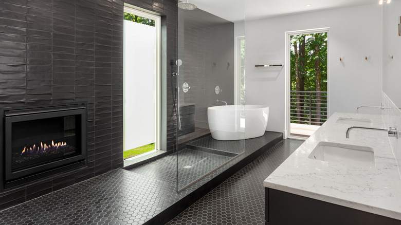 Cabinets with glass in black and white bathroom and white sinks and whitetub