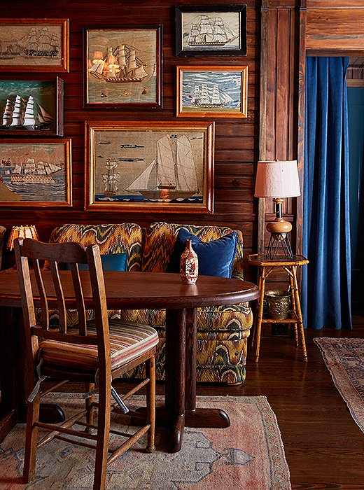 A wooden picture wall with a table lamp and chairs