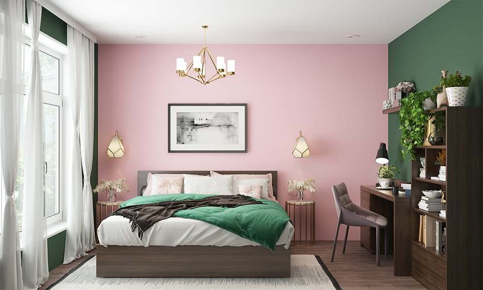 A pink and green room with lights on the wall and wooden floor and study table in corner 