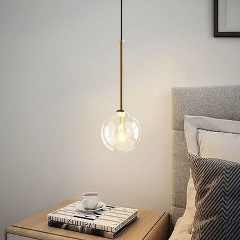 A white bedroom with glass pendent light and a side table 