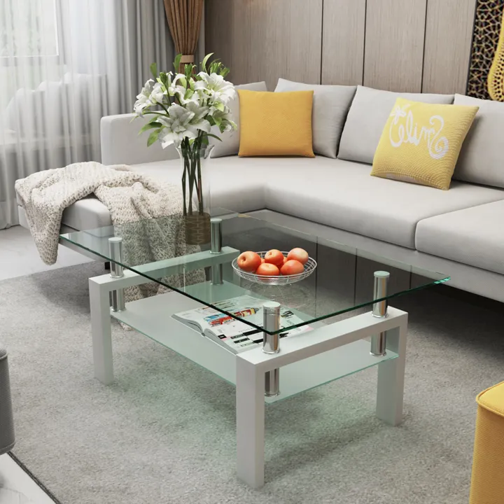 A glass table with sofa and yellow cushion on it and flower vase on the table