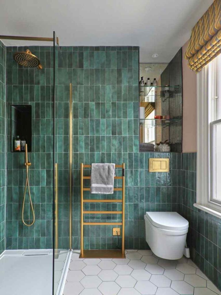 A green bathroom with gold towel rack and white windows 