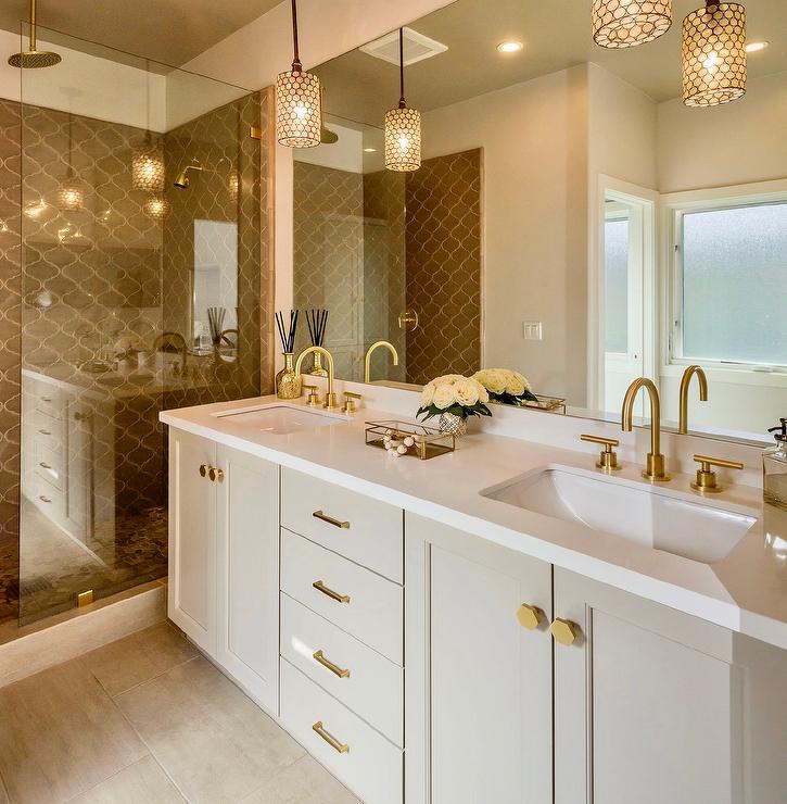 Gold faucets in grey and white bathroom and mirror on the wall 