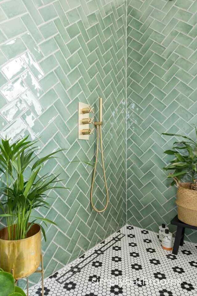 A green bathroom with gold potted plants with gold accents