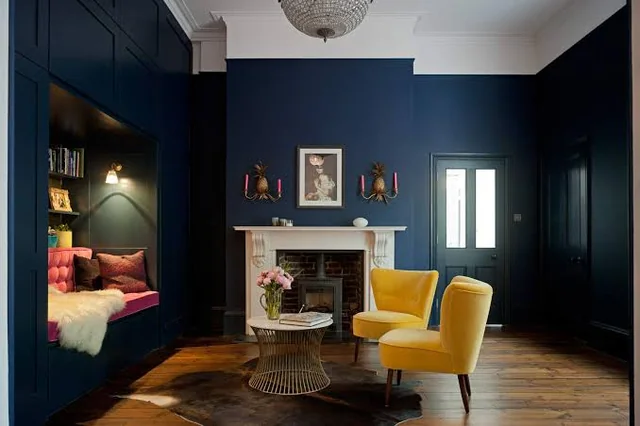 A blue living room with wooden flooring and yellow chair and table 