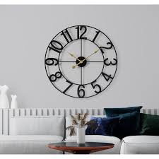 A black wall watch on the white wall and table and sof