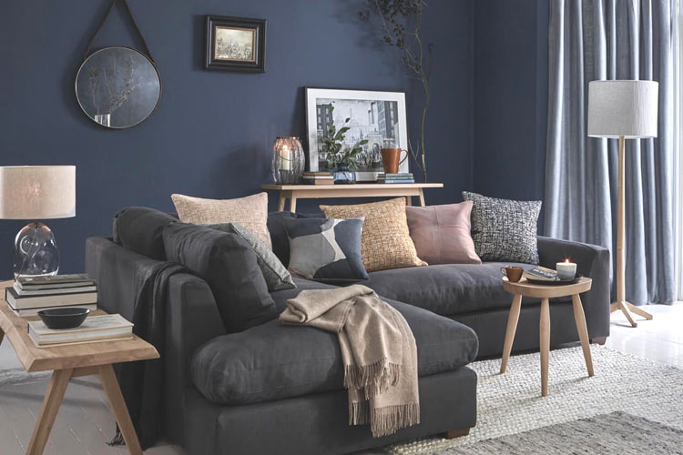 A blue living room with grey sofa and table and mirror on the wall 