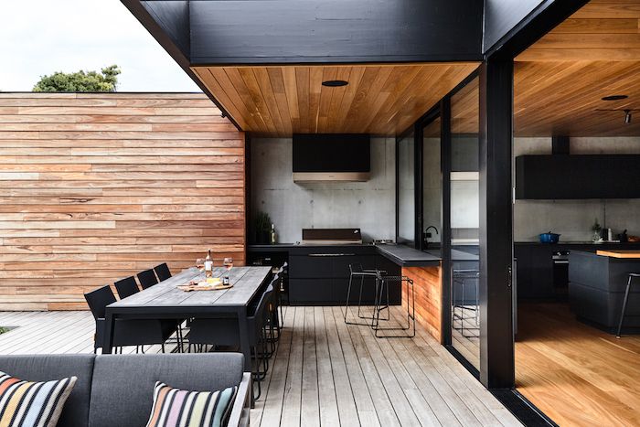 A cedar kitchen on black house and dinning table outside fo the house