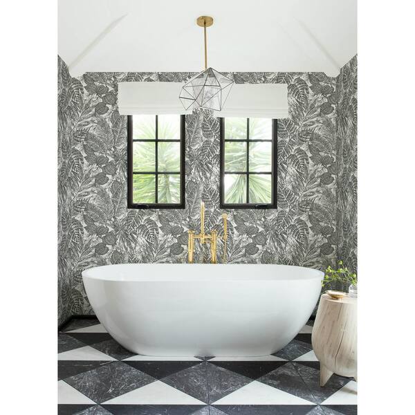 Palm leaf wallpaper in white bathtub and black framed windows in bathroom