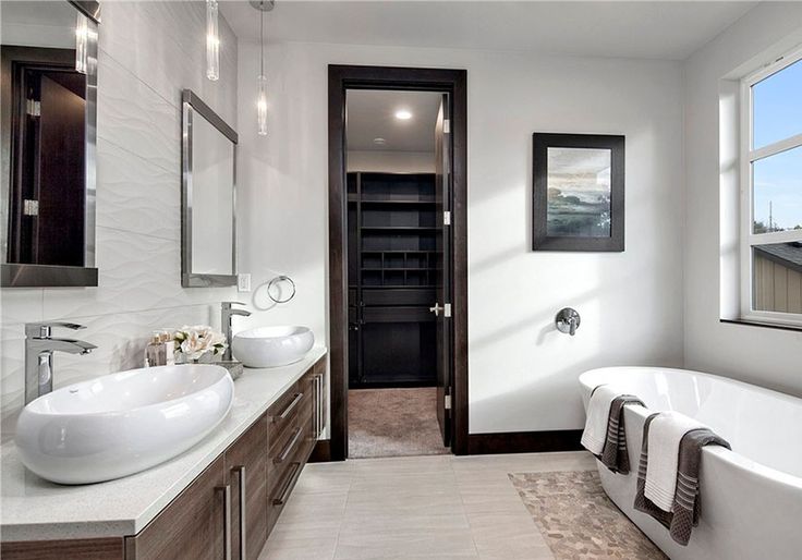 A white bathroom with wooden vanity with white counter top with black framed 