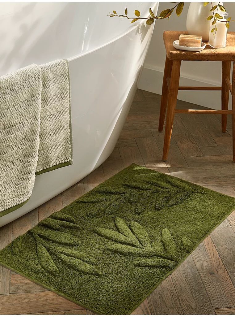 A green rug with bathtub nad wooden floor 