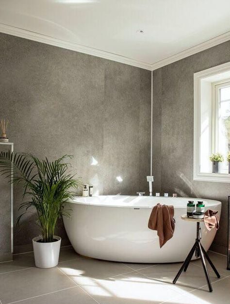 A grey bathroom with white potted plants and white bathtub 