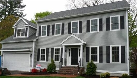 A black shutter and windows on grey house with black door