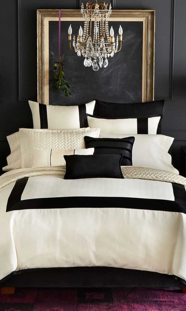 A black bedroom and beige throws and pillows and crystal chandelier
