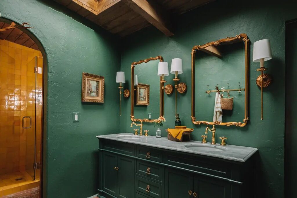 A green bathroom with golden mirror and green vanity 