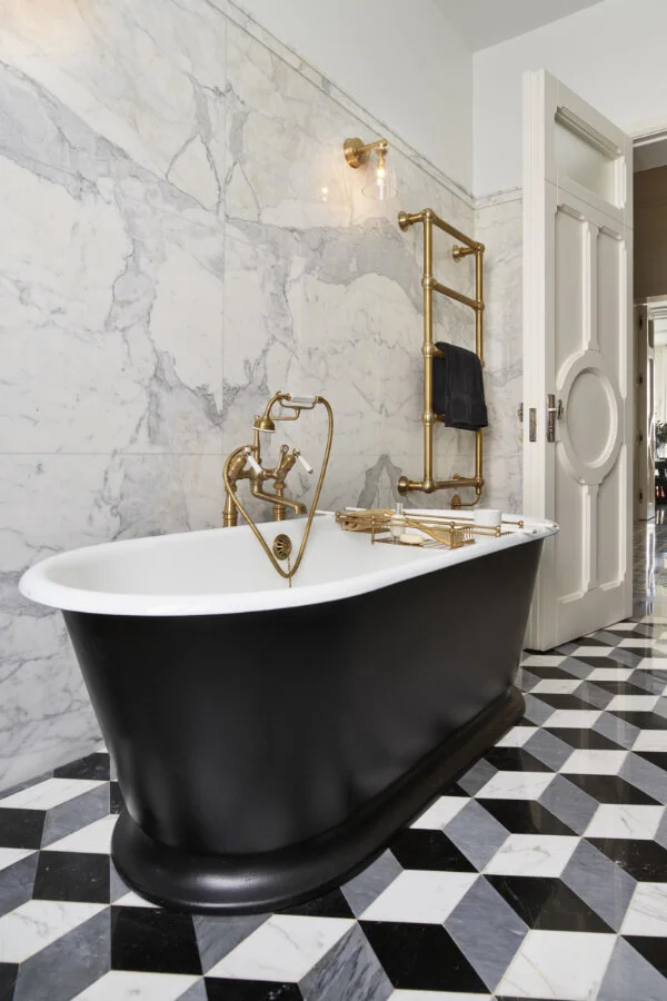A black bathtub in white bathroom and white door
