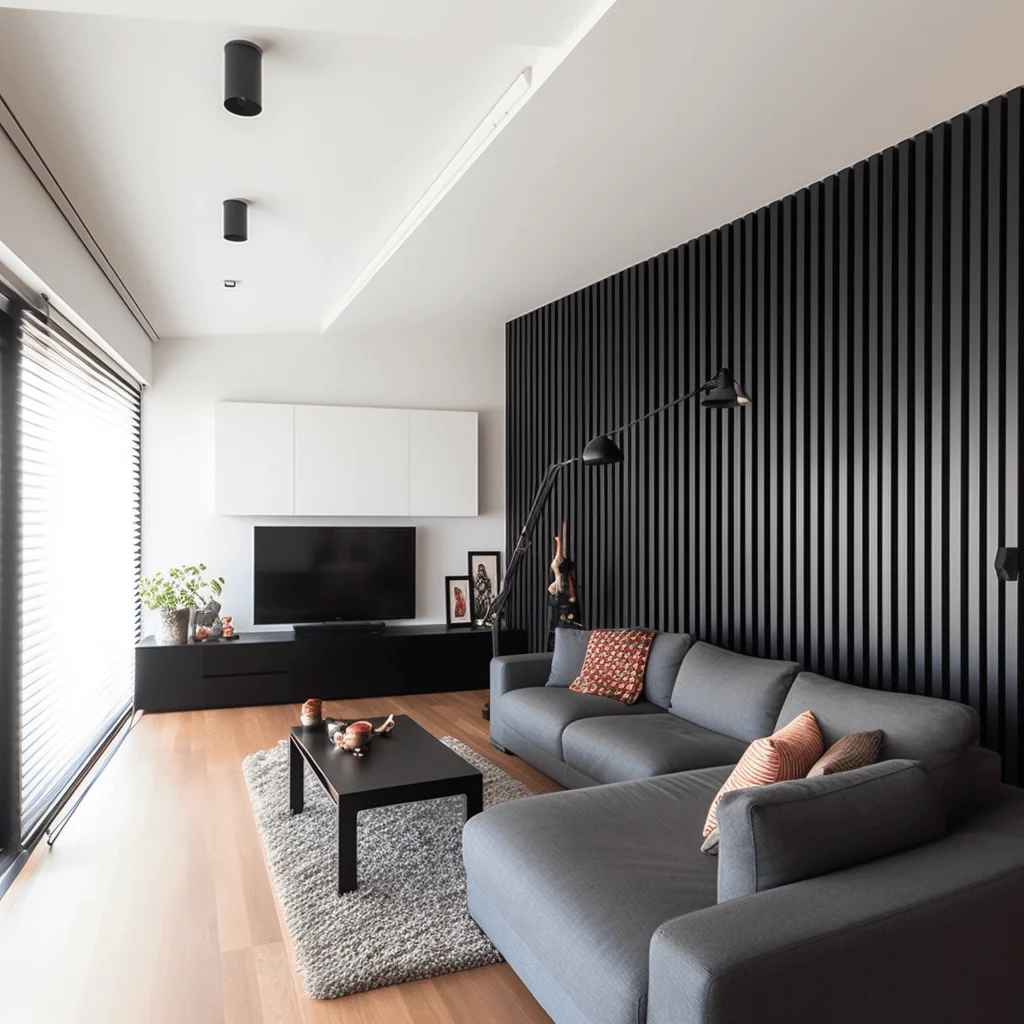 A white wall with black panels and grey sofa and table and led on the wall