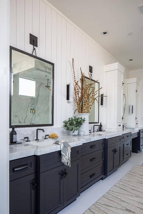 White shiplap bathroom with black hardware and mirror on the white wall