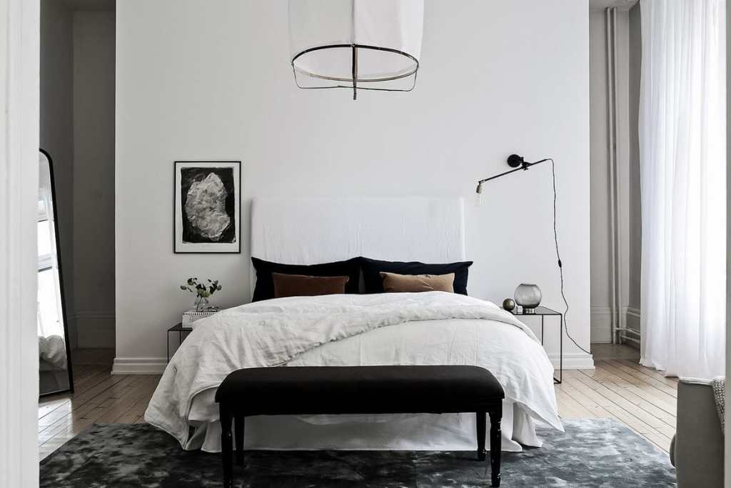 A white living room with black bed and brown pillow on the bed 