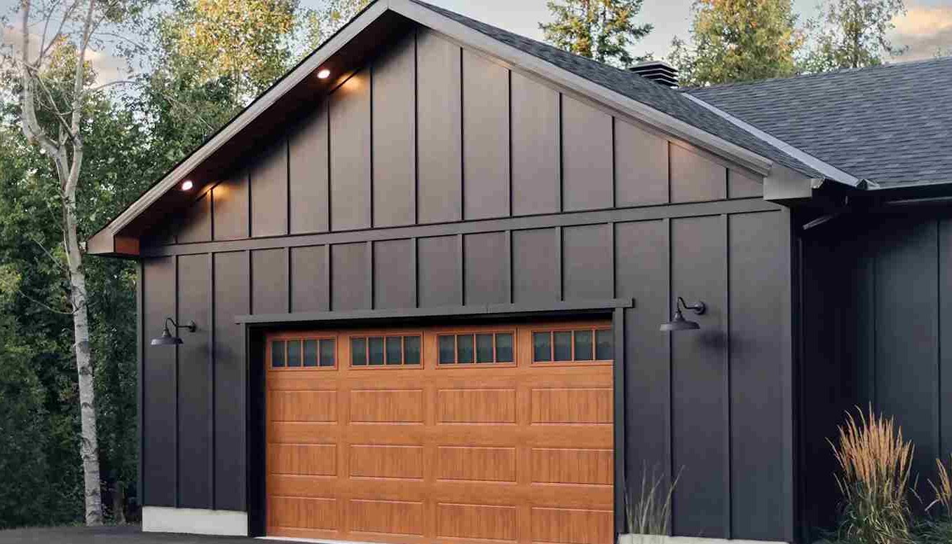 A cedar garage door on black house with lights above the wall