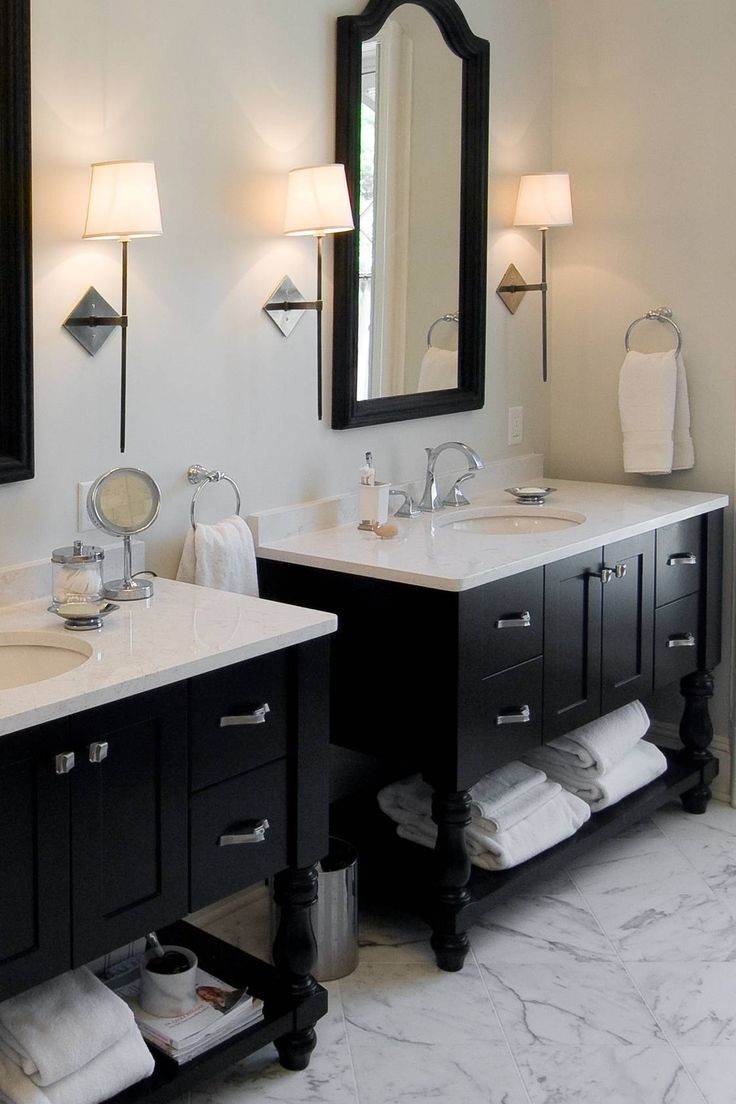 A white bathroom with black cabinets and white to and black framed mirror