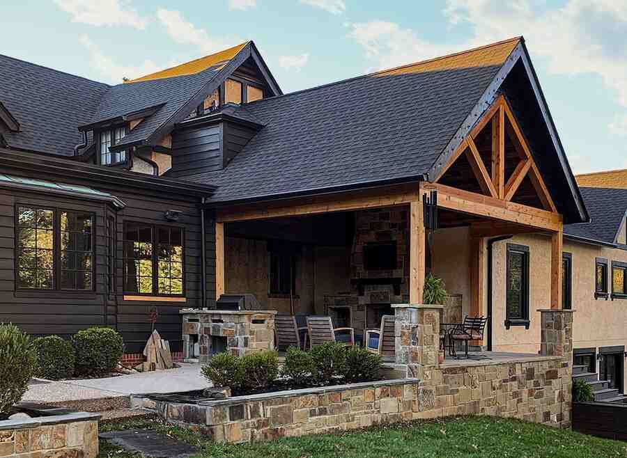 A black house with cedar accents and stone pillars