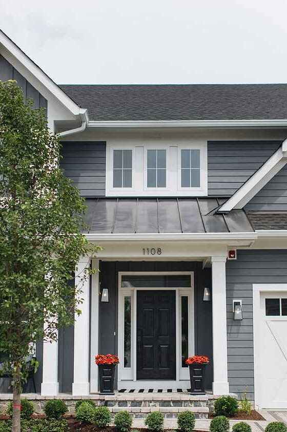 Grey house with black door and white trim and lights on the wall