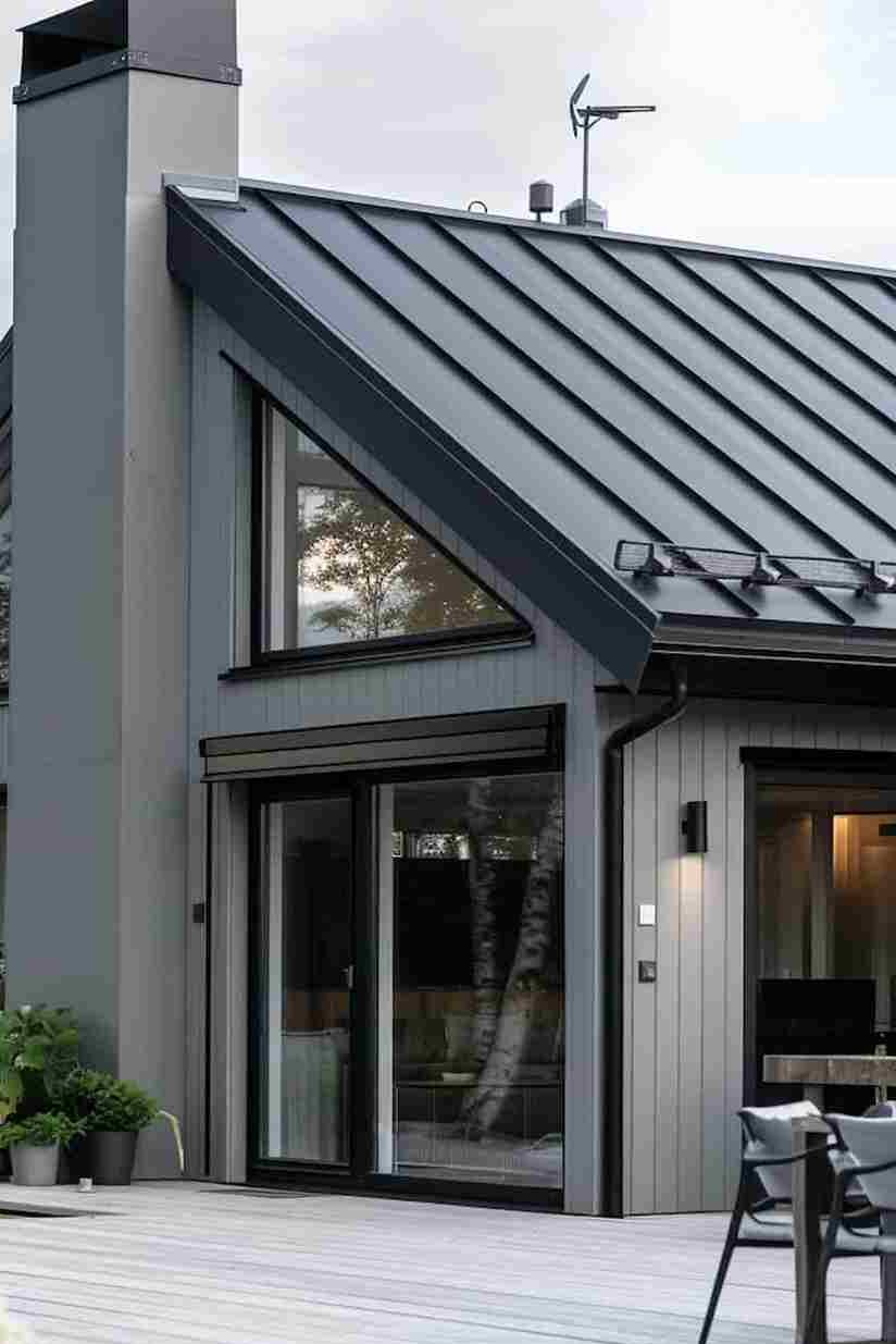A grey house with black roofline and black gutters and glass windows