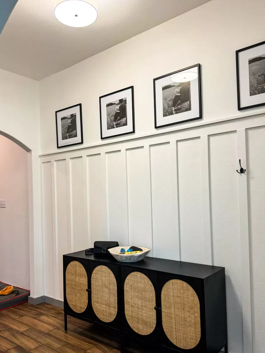 A board and batten bathroom and black and golden table and frames on the wall