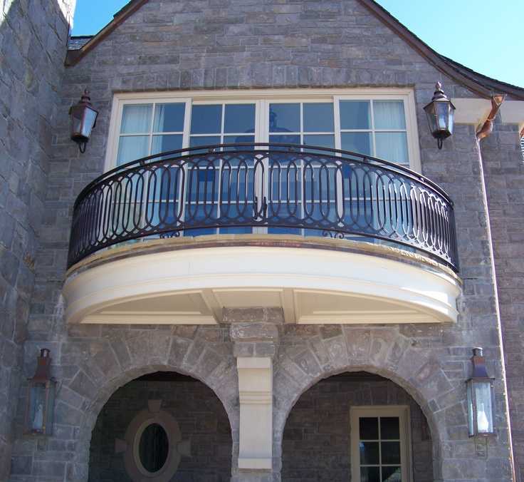 A grey house with black balcony and lights on the wall