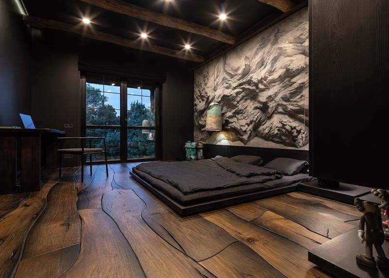 A black bedroom with wooden floor and celling lights above the wall 