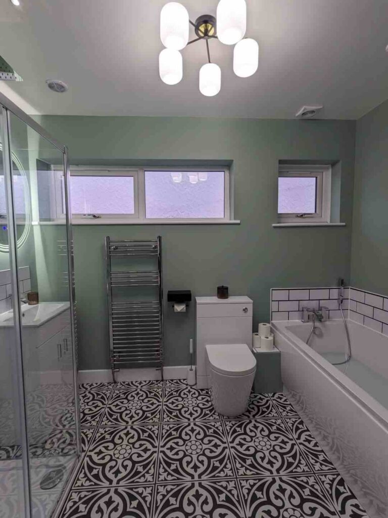 A sage bathroom with black and grey floor and white bathtub 