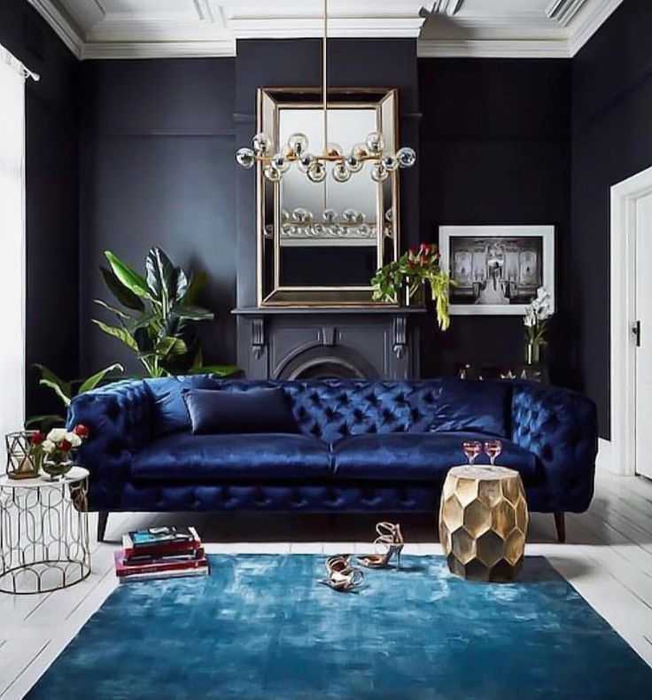 A black living with accent wall and blue sofa with cushion and blue rug on the grey floor 