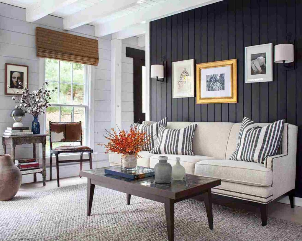 A black accent wall with grey wall and sofa with cushion and table