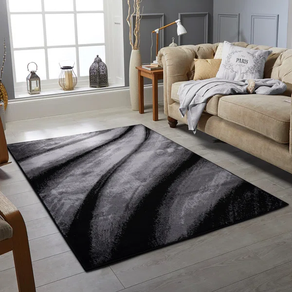 A grey living room with black and grey rug on the floor 