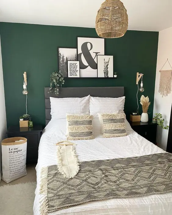 A green bedroom with black and white artwork on the wall and lights fixtures 