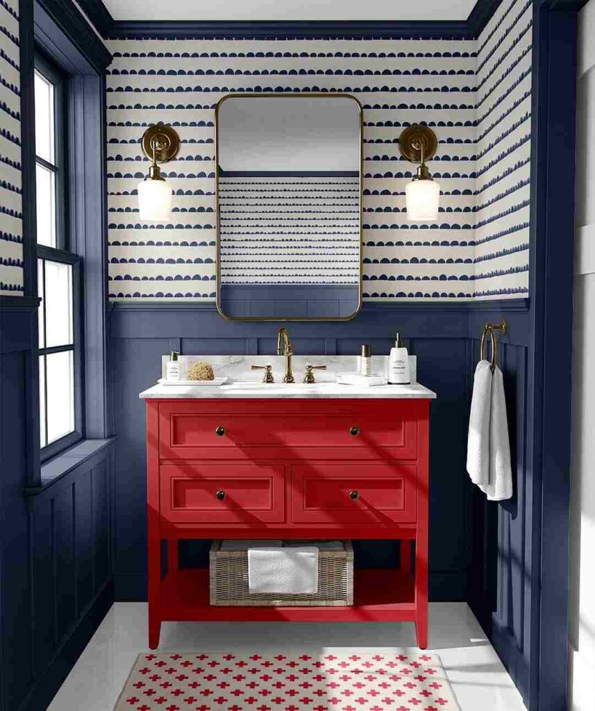 A blue bathroom with. red vanity and mirror on the wall with light fixture 