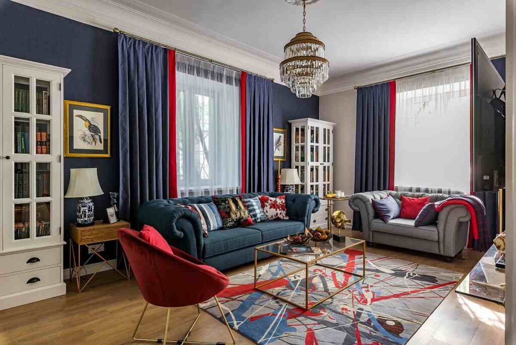A blue and grey living room with wooden floor and red accents 