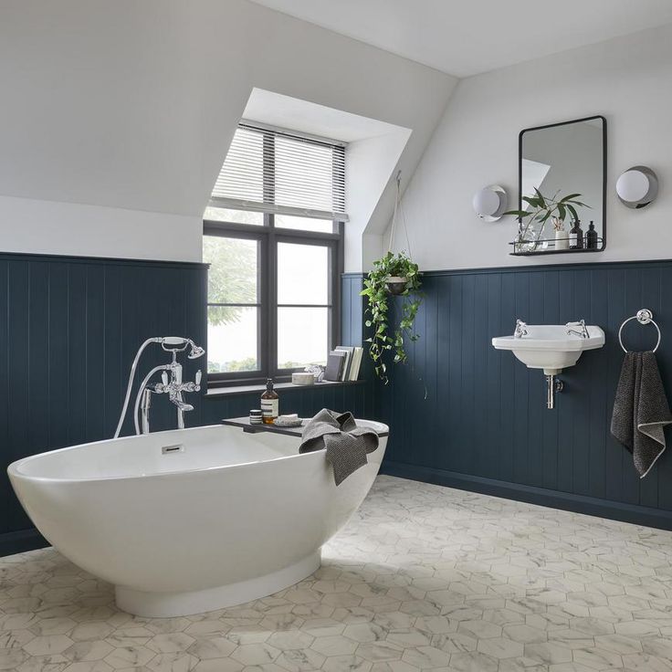 A blue bathroom panel with grey wall and white sink and bathtub 
