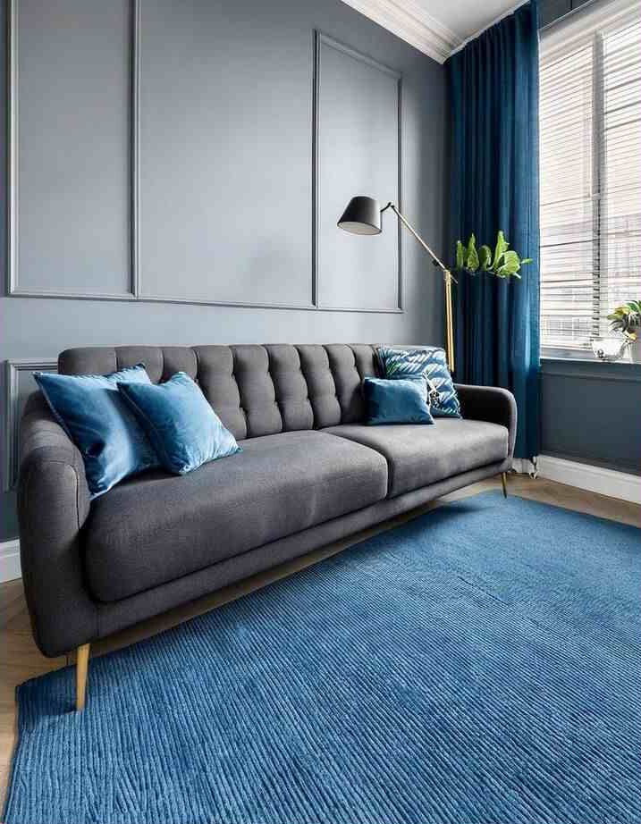 A grey living room with accents wall and sofa with cushion and rug on the wooden floor 