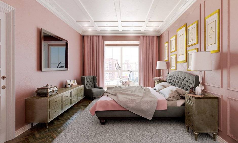 A pink bedroom panel wall and white celling and wooden side table and lamp on it 