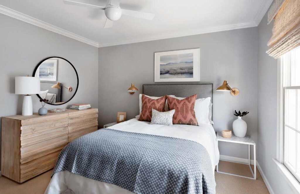 A grey bedroom with brass light and mirror on the wall 