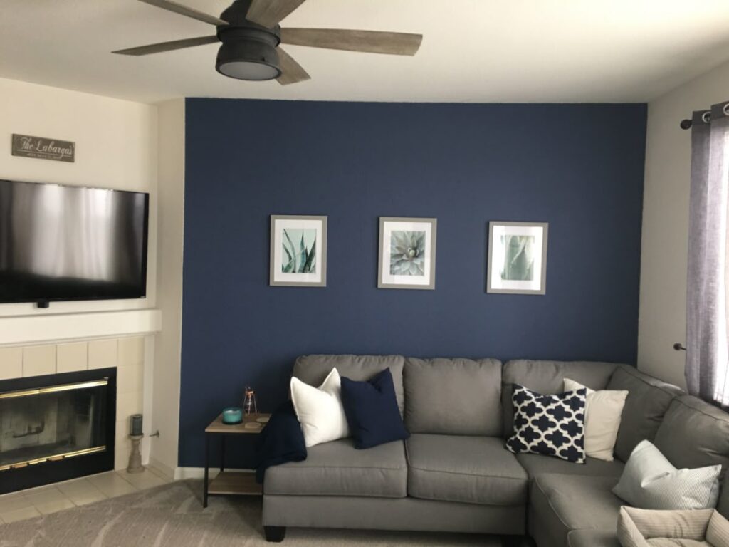 A blue and grey living room with white frames on the wall 