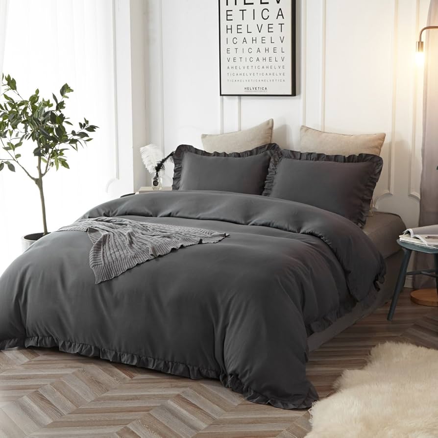 A white and grey duvet cover and wooden floor and white curtains 